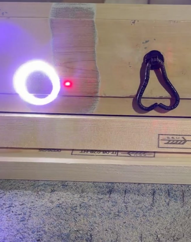 META laser in operation — laser plasma visible mid-pass on a timber substrate